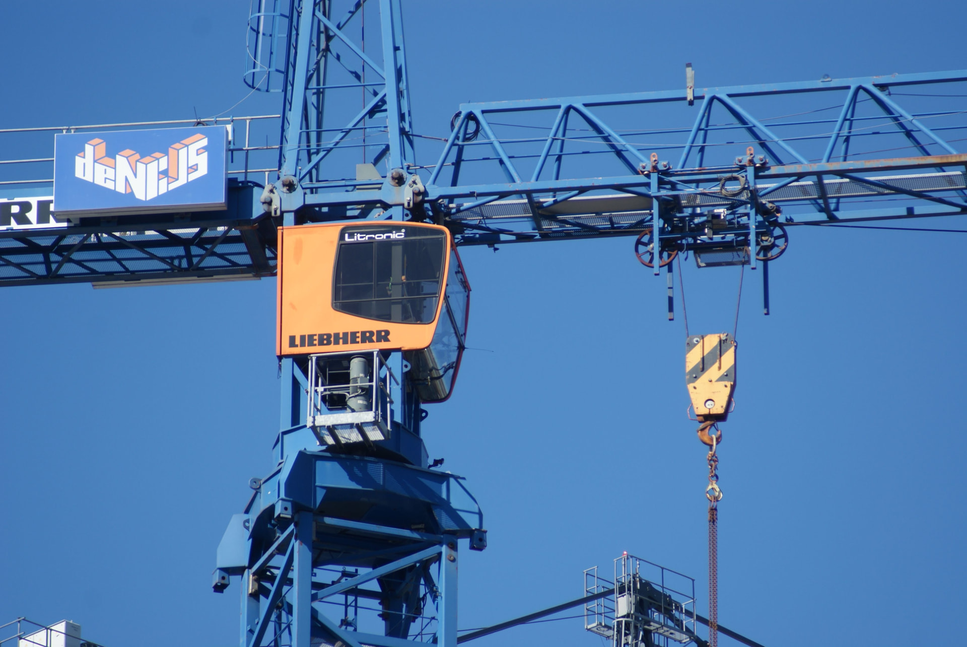 Guindaste industrial Liebherr com cabine laranja contra céu azul — operação de bens de capital atendida pela Vale IT Solutions.