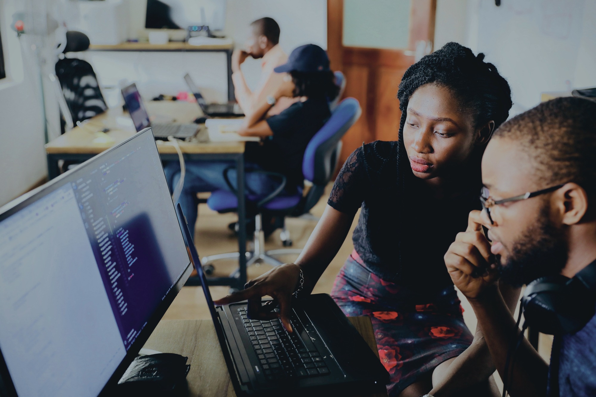 Equipe de desenvolvimento colaborando em notebook com código exibido — ambiente corporativo Liebherr atendido pela Vale IT Solutions.